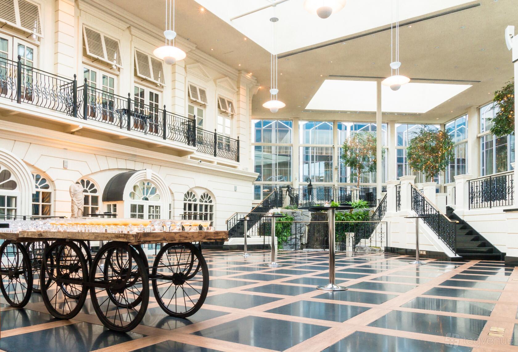 A spacious hotel hall with glass ceiling, black-and-white checkered flooring, and decorative balconies at Radisson Blu Hotel, London Heathrow.