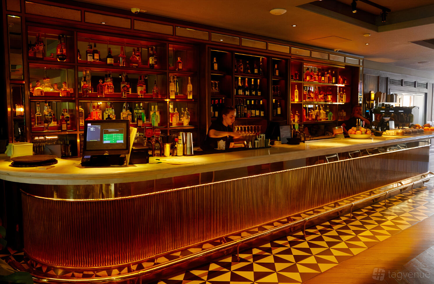 An event venue with a long illuminated marble bar, mirrored shelves, and geometric floor tiles at Oneninetyfour.