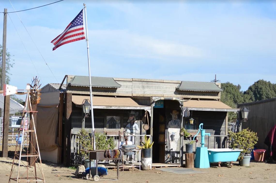 A rustic barn venue with weathered wood siding, American flag, and outdoor vintage decor at Surfside Ranch.