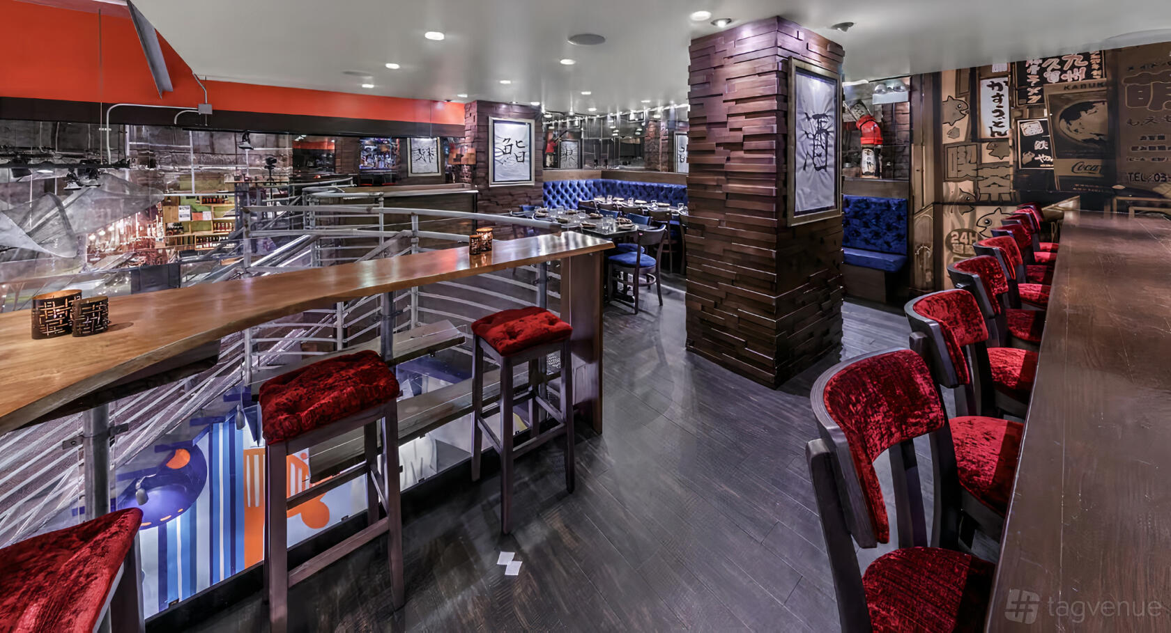 A restaurant interior with blue tufted banquette seating, red velvet bar stools, and wood panel accents at Union Sushi + Barbeque Bar.