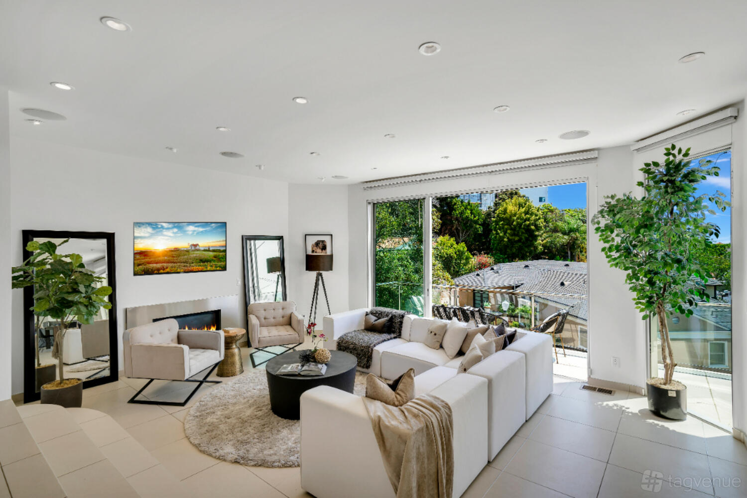 An event venue with a spacious living area, white sectional sofa, fireplace, large windows, and indoor plants at The Crescent Villa.