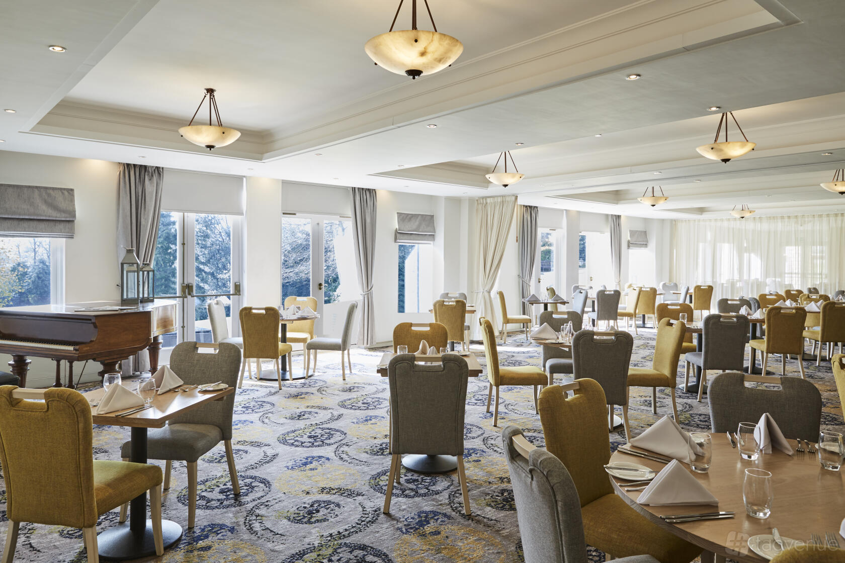 A function room with floor-to-ceiling windows, round tables set for dining, and a grand piano at Mercure Sheffield Kenwood Hall Hotel & Spa.