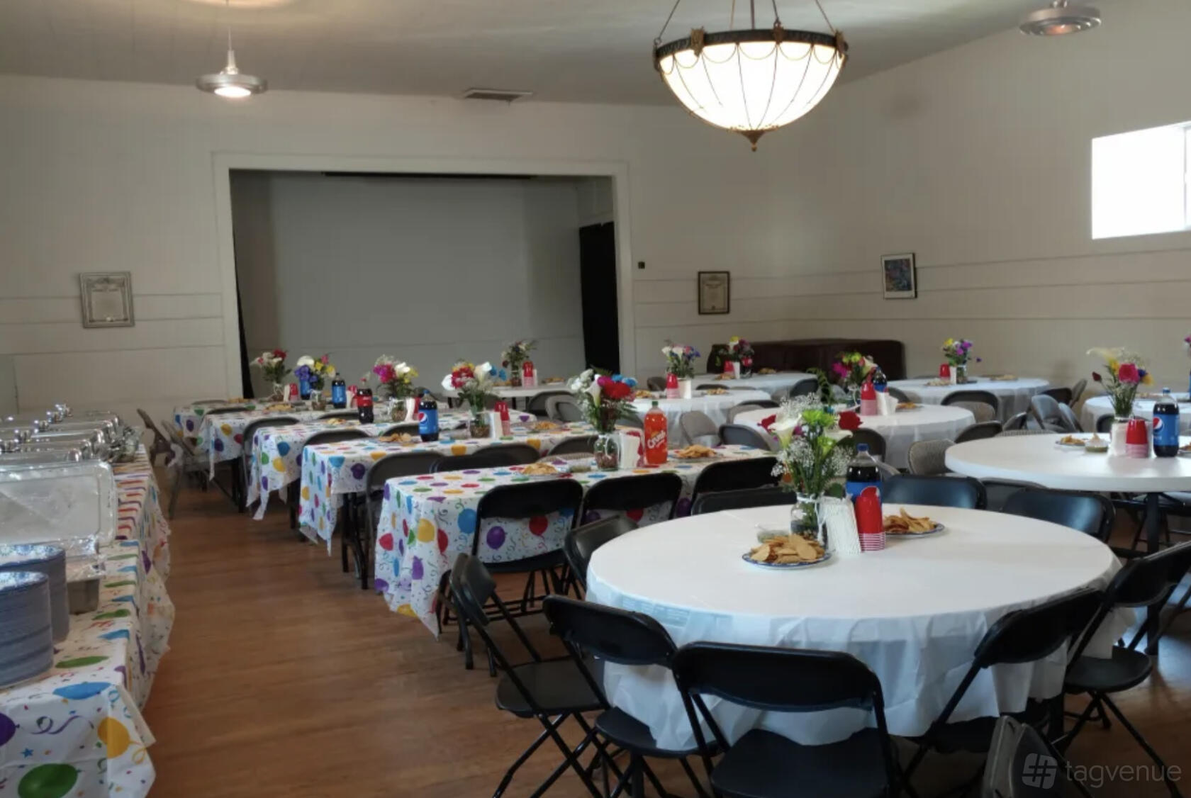 An event venue with round tables covered in colorful polka dot tablecloths and folding chairs at West Seattle Veteran Center.