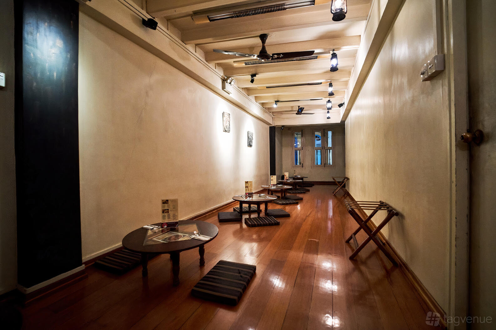 An event space with low tables, floor cushions, and polished wooden floors at Lagnaa Barefoot Dining.
