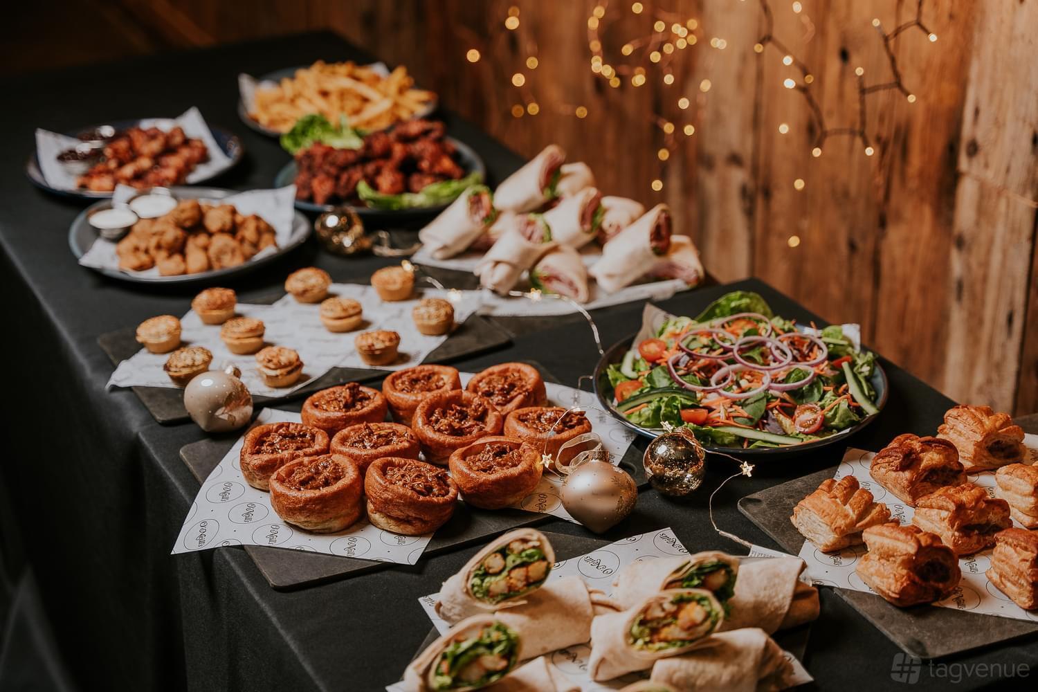 An event space in a pub with a buffet of pastries, wraps, salads, and appetizers on black tablecloths at The Royal.