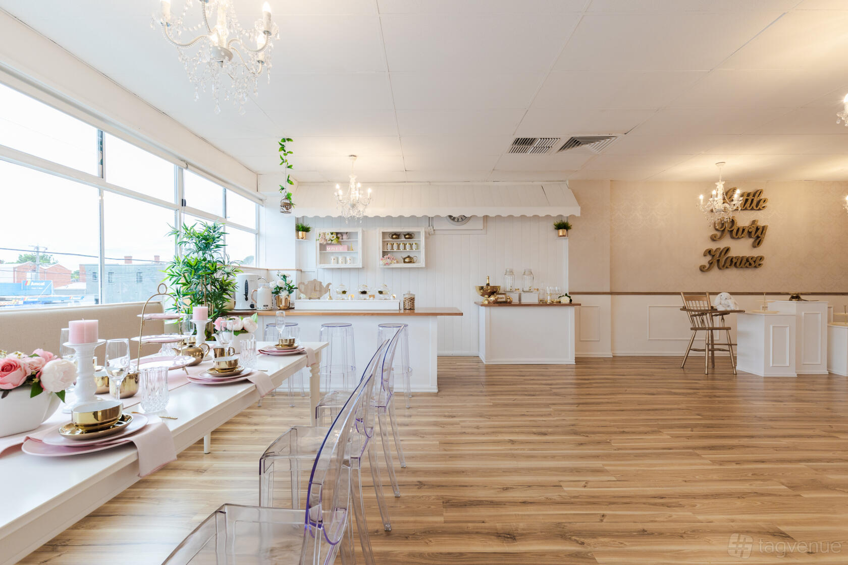 An event venue with chandeliers, clear acrylic chairs, floral centerpieces, and wood flooring at Little Party House.