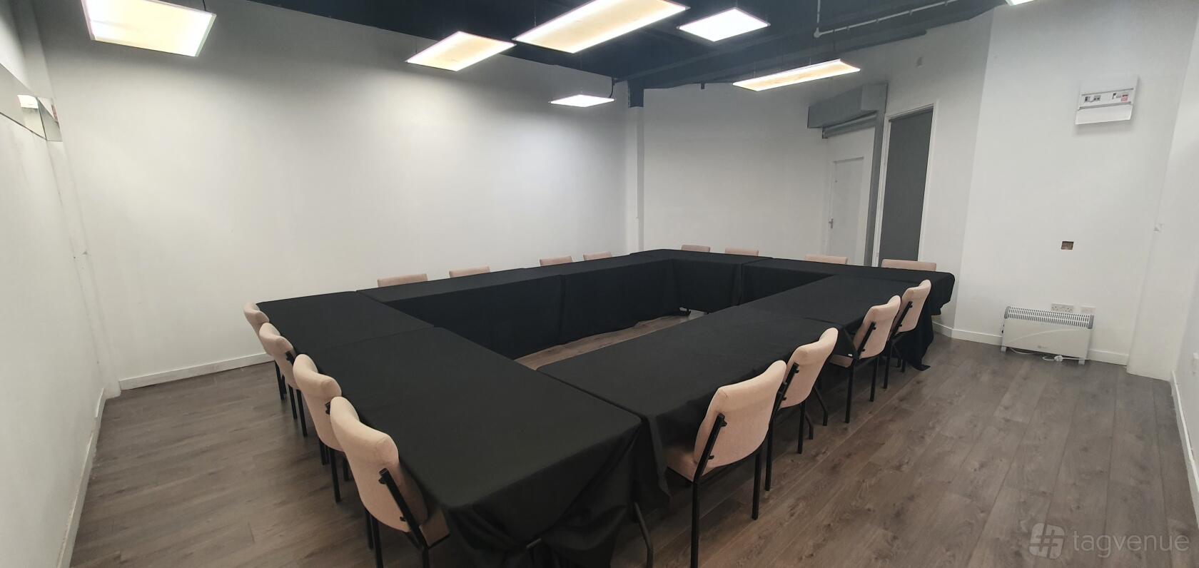 A meeting room with U-shaped tables covered in black linens and beige chairs at Glasgow Rooms.
