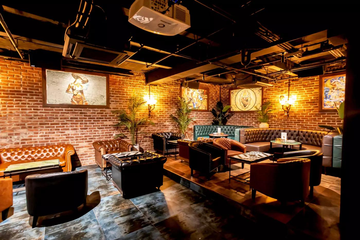 A restaurant lounge with exposed brick walls, leather sofas, and framed artwork at Silent H.