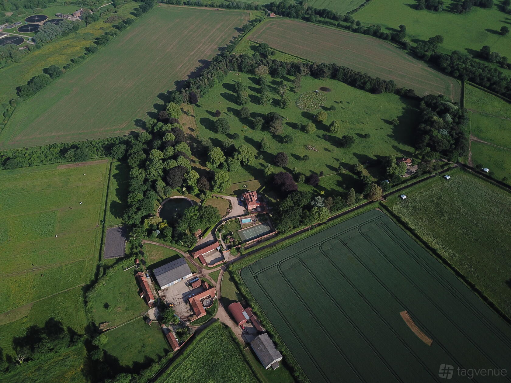 A country house surrounded by expansive green parkland, mature trees, and farmland at Bullard's Farm.