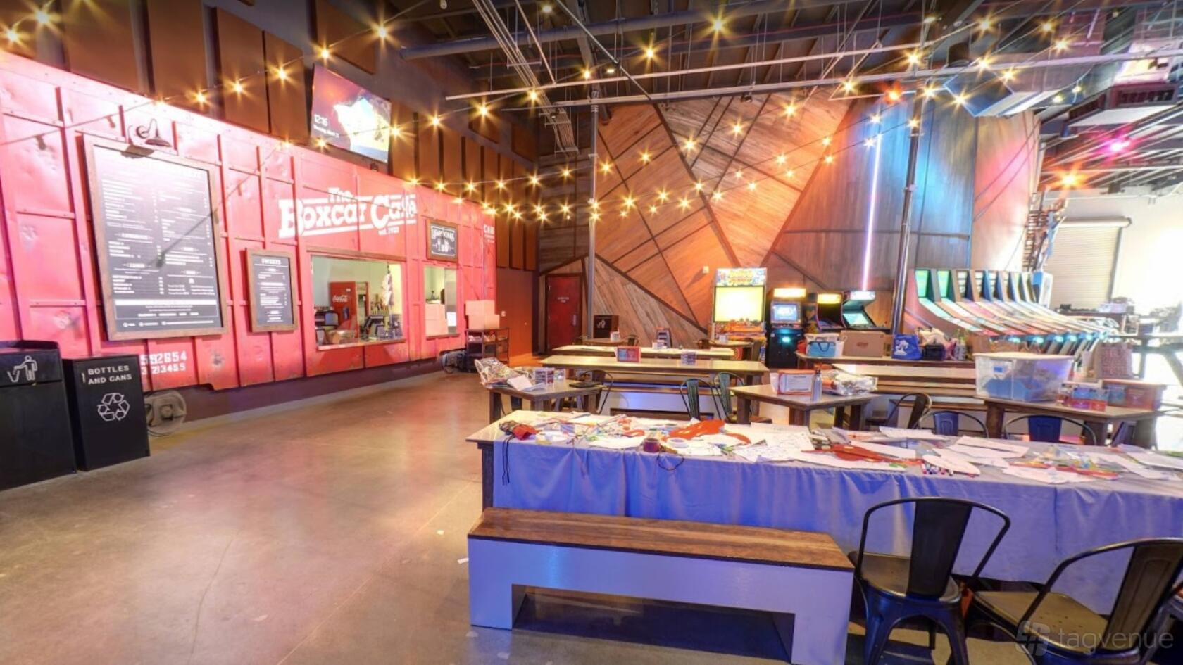 An event venue with arcade games, string lights, and communal tables at Two Bit Circus.