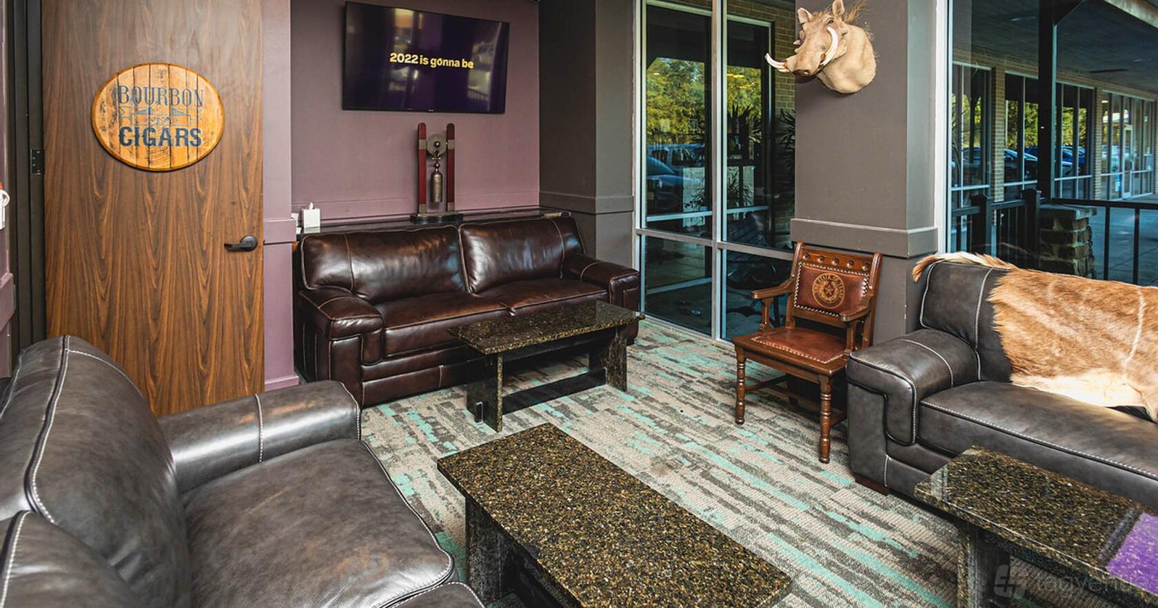 A lounge with leather sofas, a wooden armchair, wall-mounted TV, and large windows at Mirage 38.