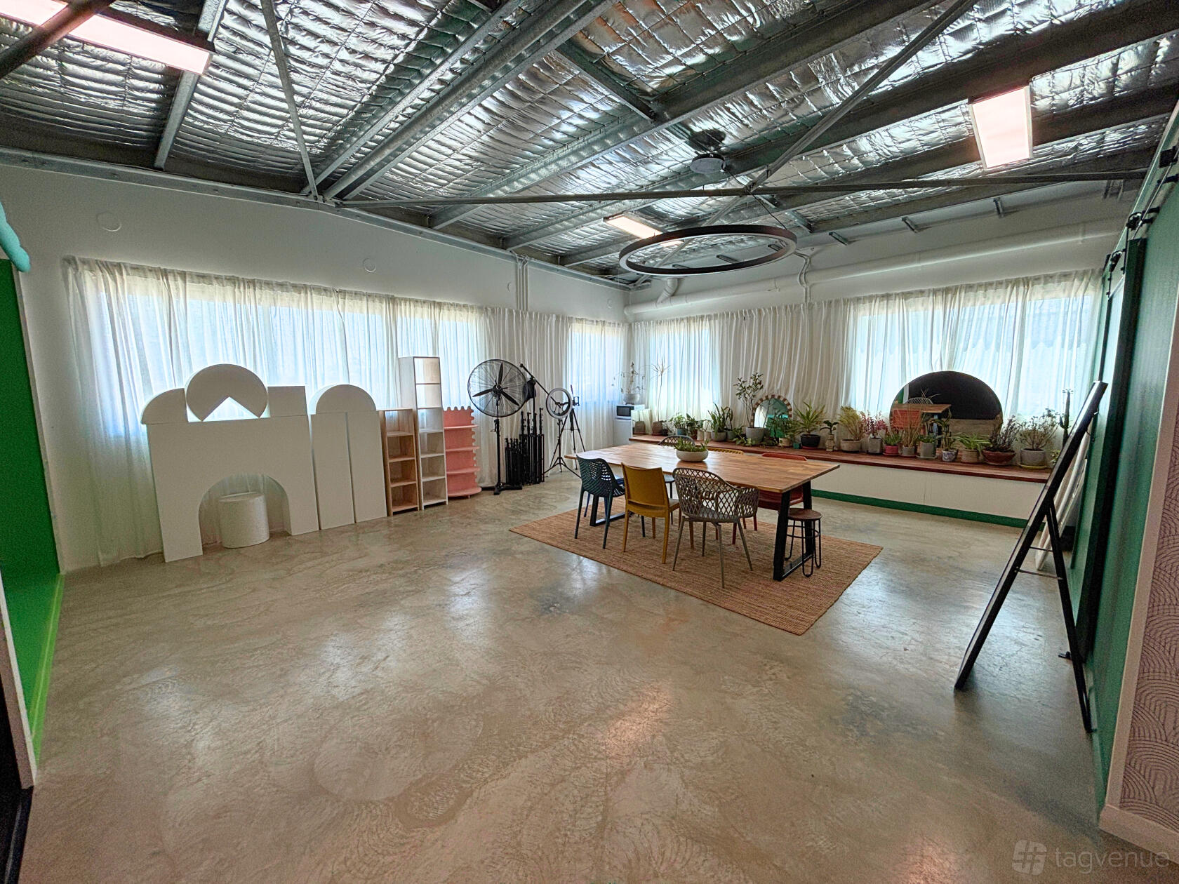 A photo studio with polished concrete floors, exposed ceiling, large windows and mixed seating at Cudan Studio.