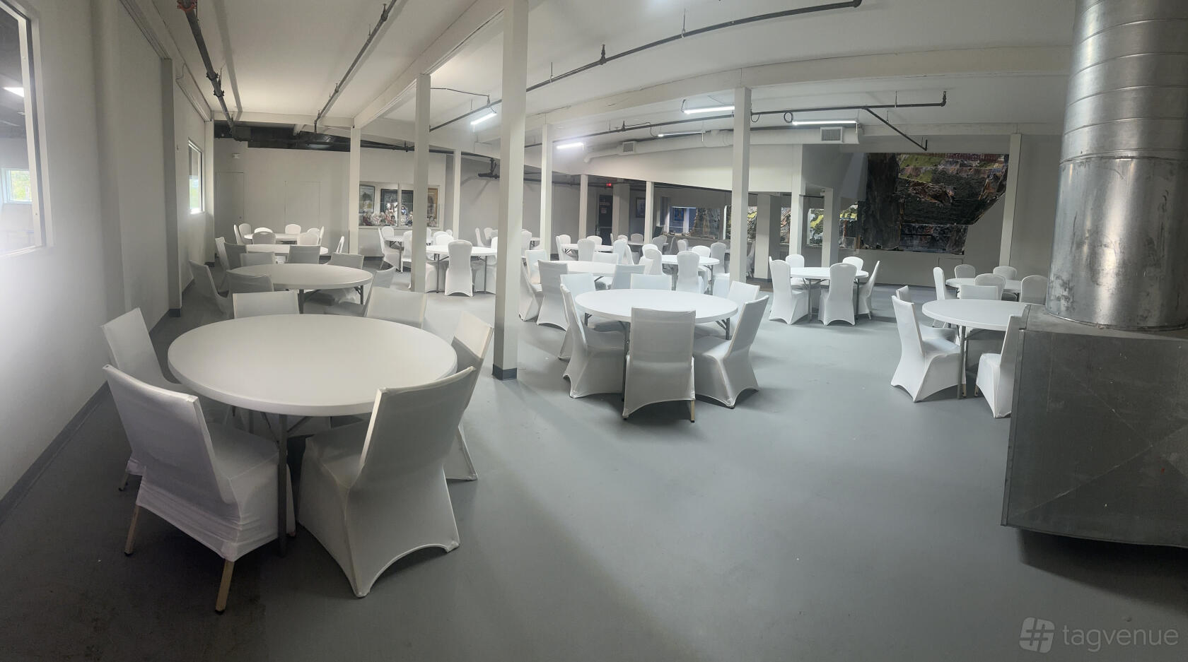 An event space with round tables, white chairs, and bright overhead lighting at Northlandz Flemington Station.