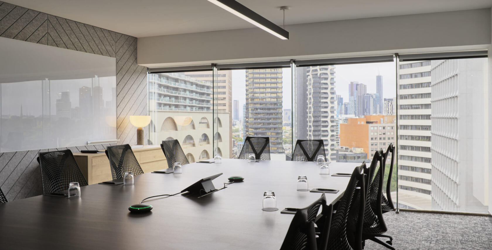 A coworking space with floor-to-ceiling windows, city skyline views, and a boardroom table at Hub St Kilda Road.