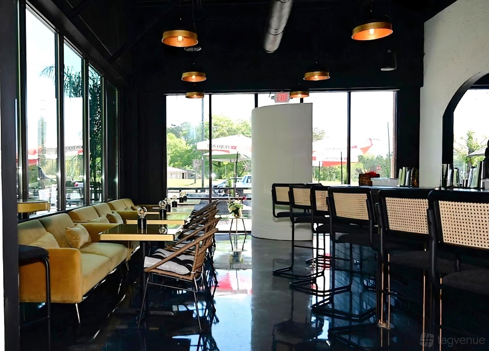 A restaurant with floor-to-ceiling windows, black ceilings, a gold sofa, and a marble bar at Access Restaurant and Lounge.