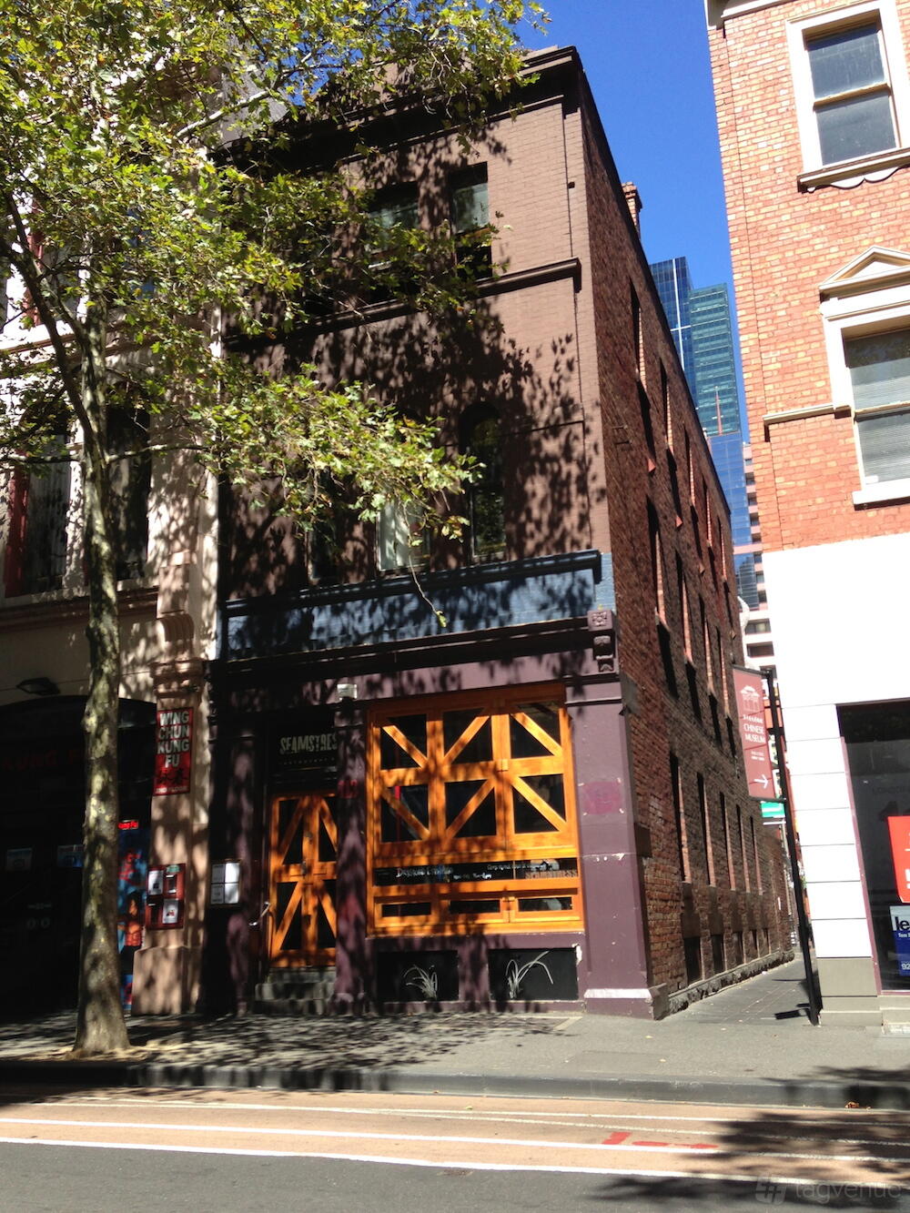 A restaurant exterior with a brick façade, large wooden double doors, and upper arched windows at Seamstress Restaurant & Bar.