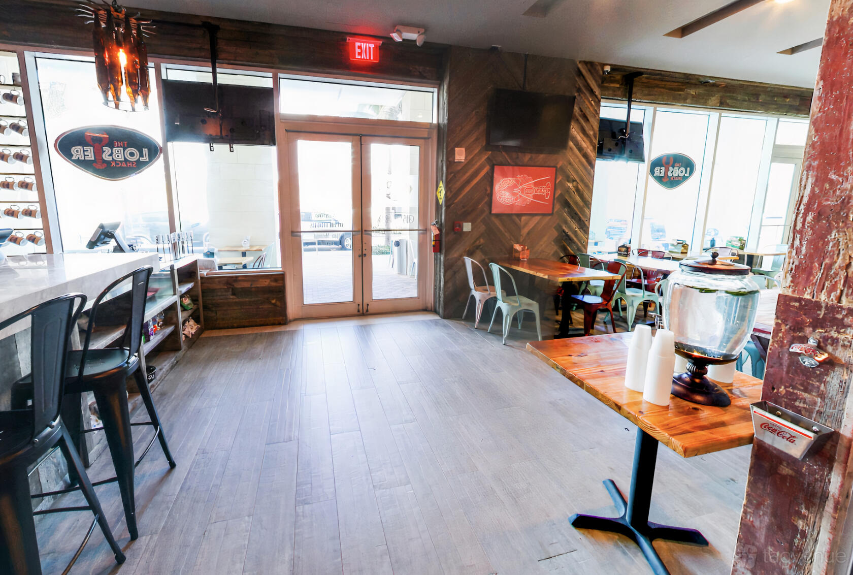 A restaurant with wood accents, metal chairs, large windows, and a self-serve beverage station at The Lobster Shack.