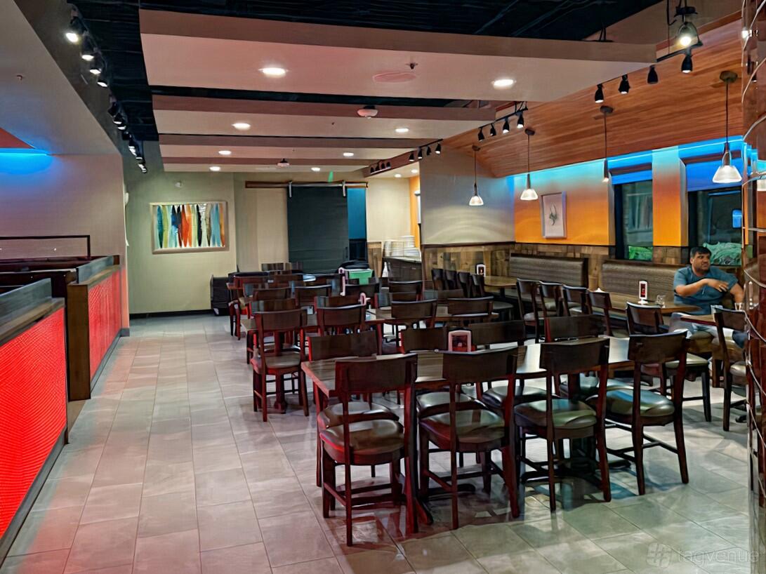 A restaurant dining area with wooden chairs, pendant lighting, and colorful wall art at Alings Chinese Bistro.