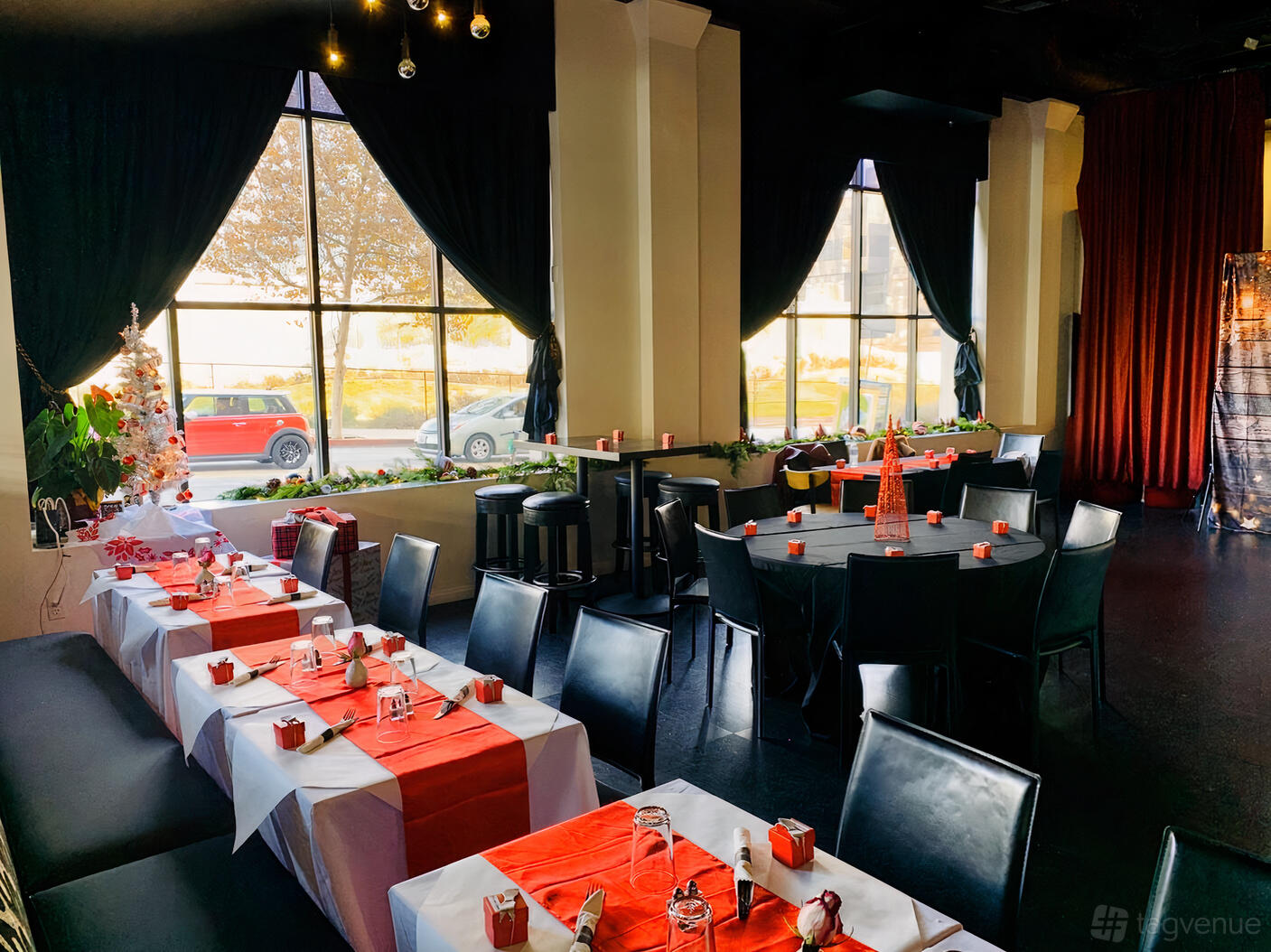 An event space with large windows, red table runners, and black chairs at Hill Street Sports Bar & Restaurant.