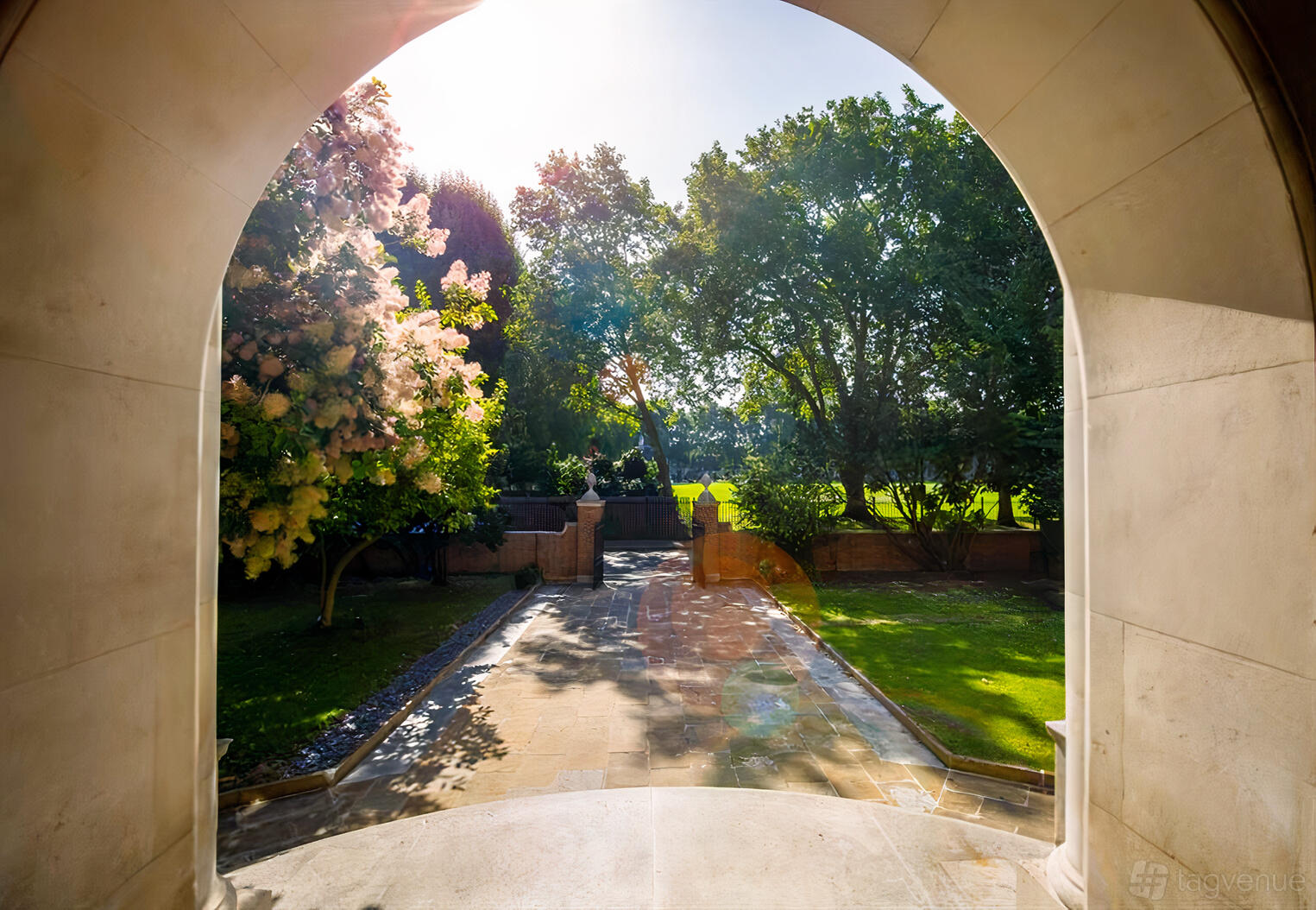 An outdoor hotel space with a stone pathway, manicured lawns, and mature trees at The Wellington by Blue Orchid.