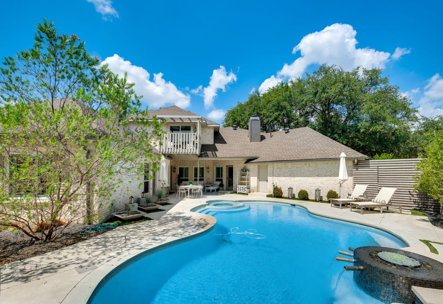 A versatile event space with a curving swimming pool, lounge chairs, and covered patio at Award Winning Water Front Home.