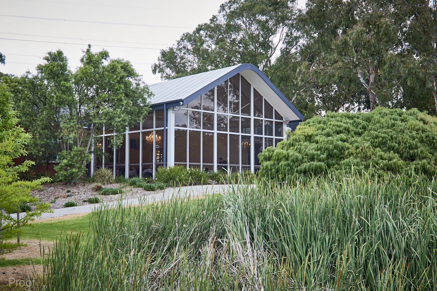 A versatile event space with tall glass windows and surrounded by lush greenery at No 1 Events- Malvern.