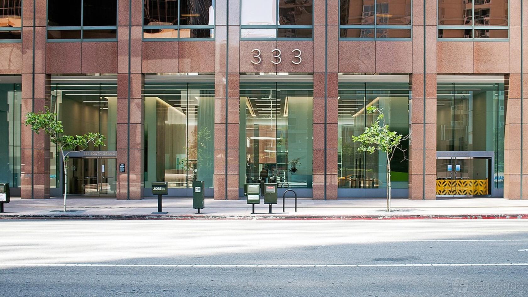 A meeting centre with floor-to-ceiling glass windows and red stone facade at Indie Desk.