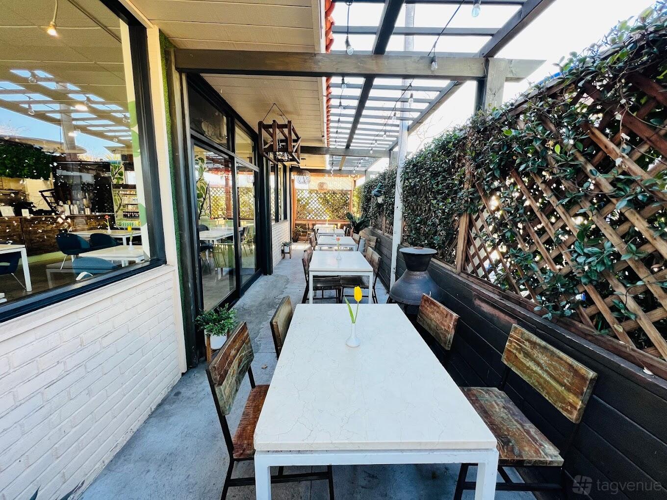 A restaurant terrace with white tables, wooden chairs, and a trellis wall at Z Garden Mediterranean Cuisine.