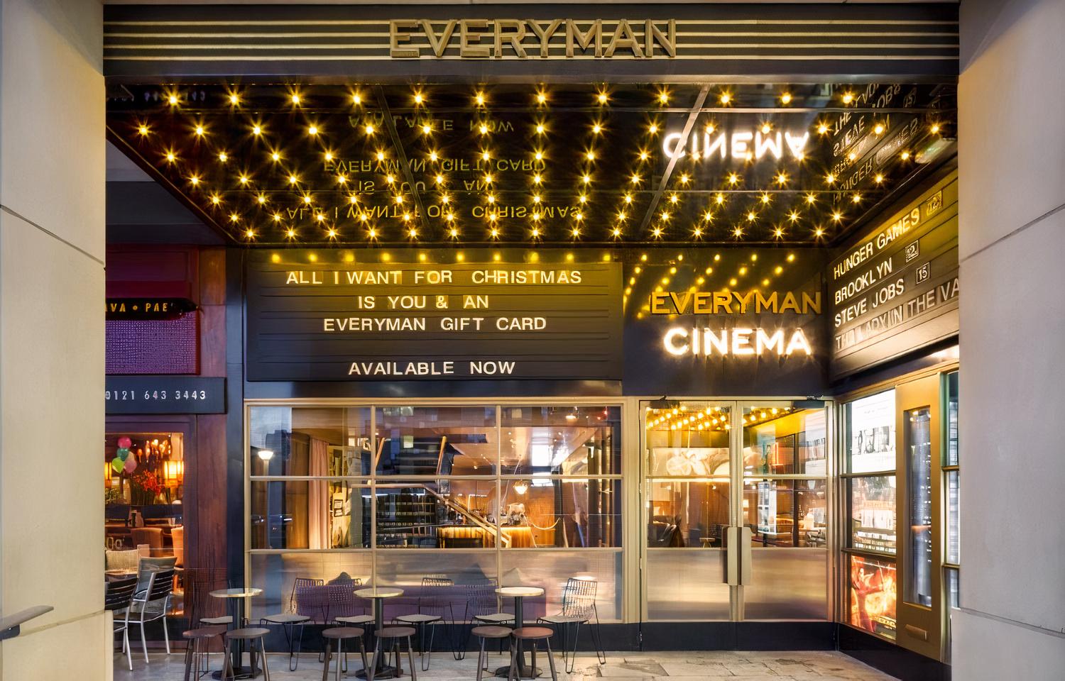 A cinema entrance with marquee lights, glass doors, and a movie sign at Everyman Birmingham Mailbox.