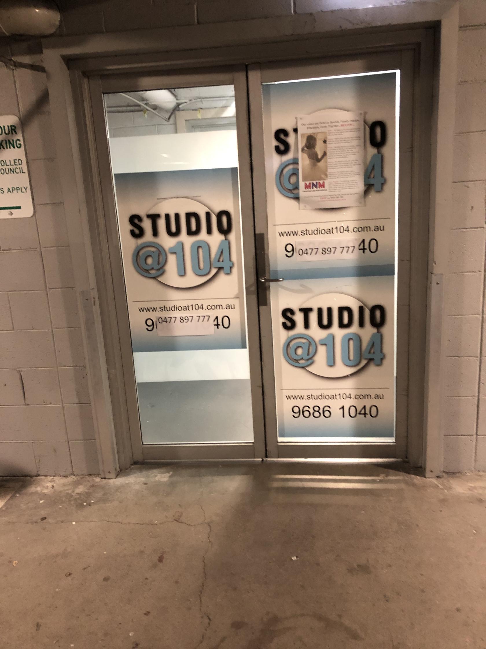 A dance studio entrance with frosted glass doors and bold signage at Studio at 104.