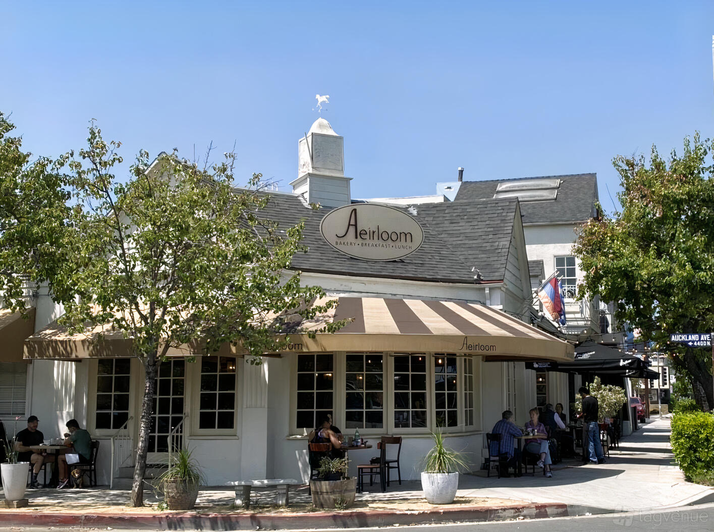 A café with an outdoor seating area shaded by striped awnings at Aeirloom Bakery.