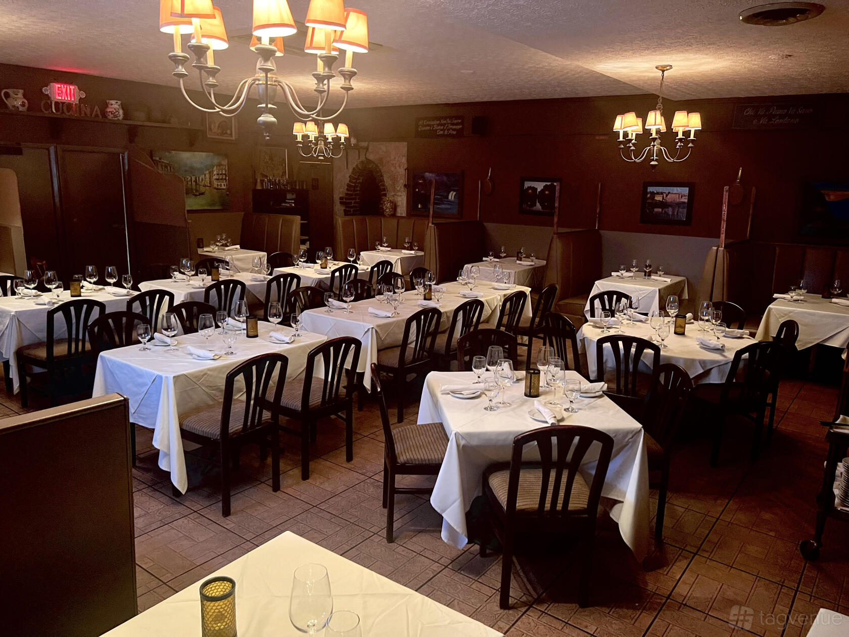 A restaurant event space with white tablecloths, dark wooden chairs, and chandelier lighting at Nino's Italian Restaurant.