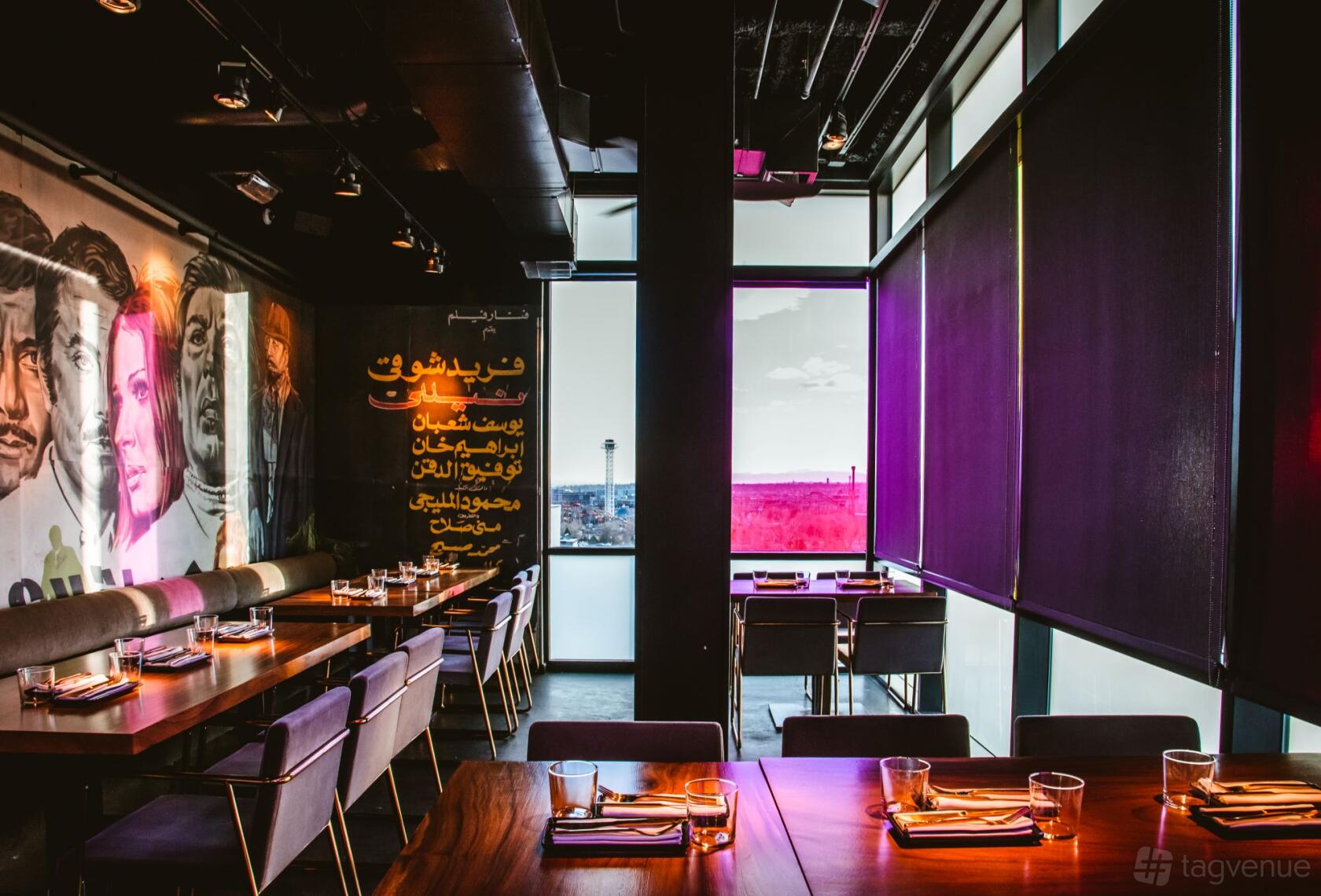 A dining room with mural-covered walls, floor-to-ceiling windows, and long wooden tables at EL Five.