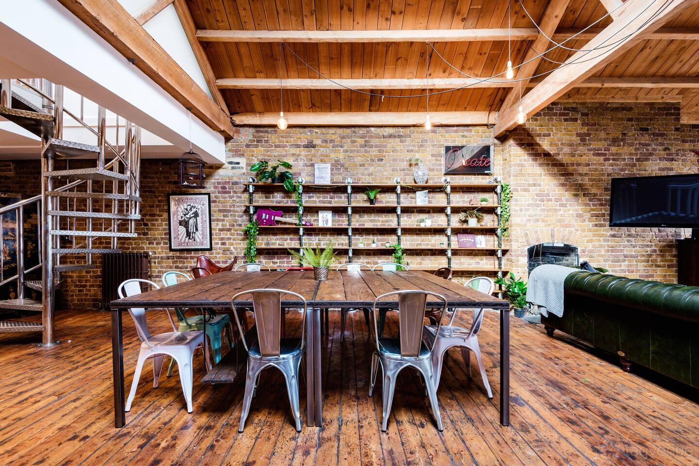 A loft with exposed brick walls, wooden floors, industrial metal chairs, and open shelving at The Loft - w. Epic Roof Terrace & Views.