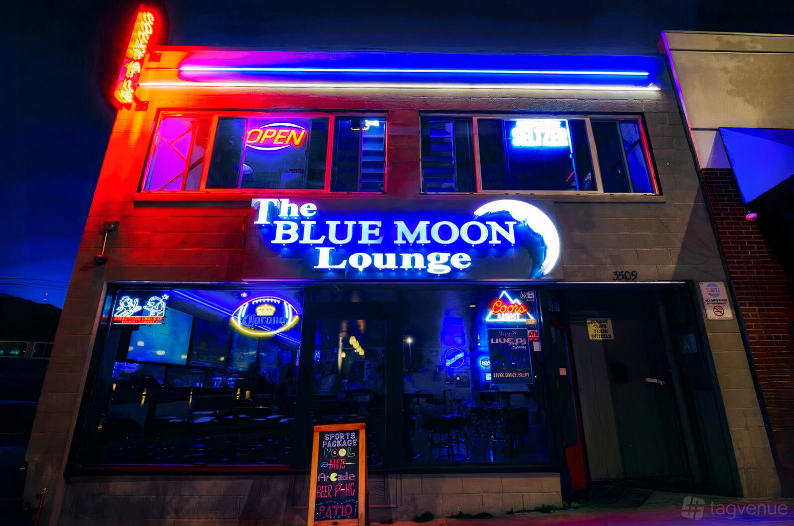 A pub with neon signage, large front windows, and illuminated blue lighting at The Blue Moon Lounge.