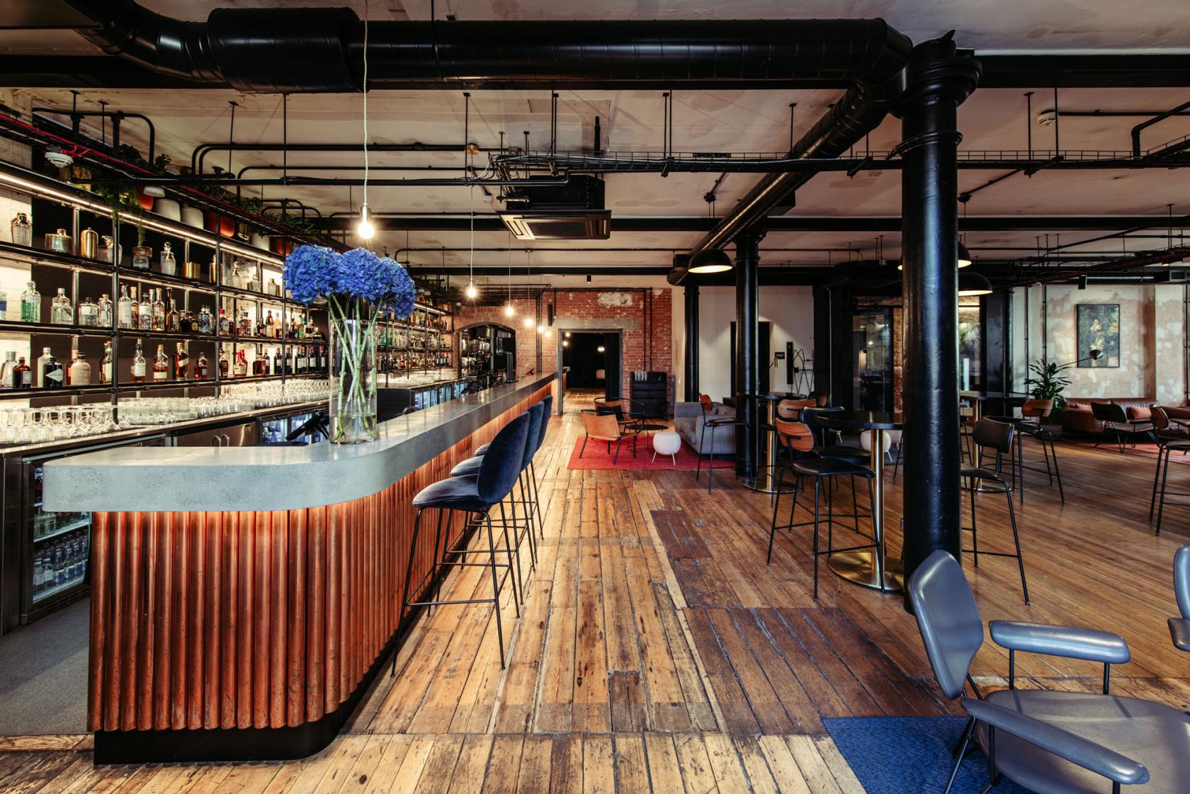 An event venue with a long concrete bar, wooden floors, high stools, and industrial accents at The Ministry.