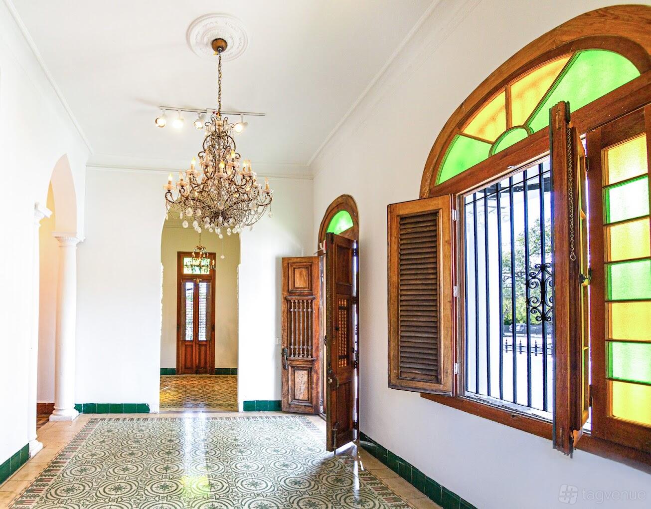 An event venue with a crystal chandelier, arched doorways, and stained glass windows at Villa Paula Miami.