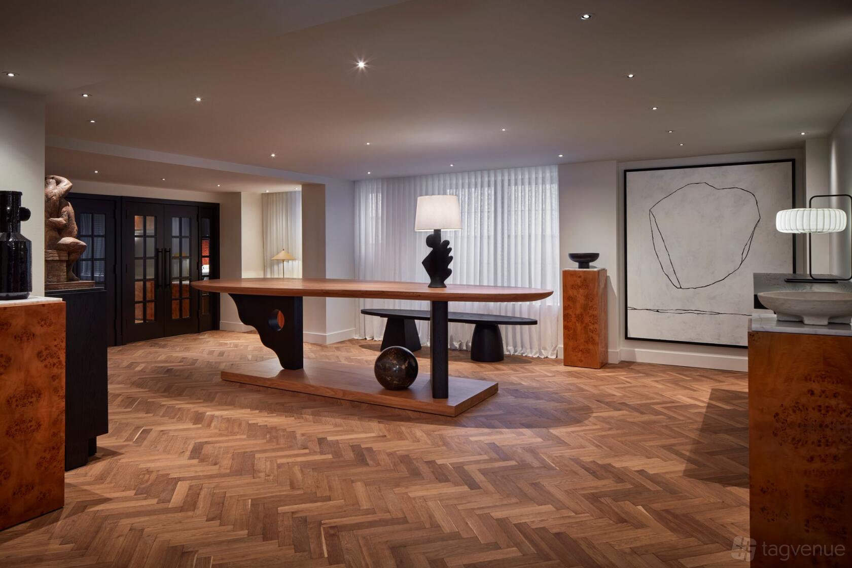 A hotel gallery with herringbone wood flooring, modern sculptures, and large abstract artwork at Lyle Washington DC - 1st floor.
