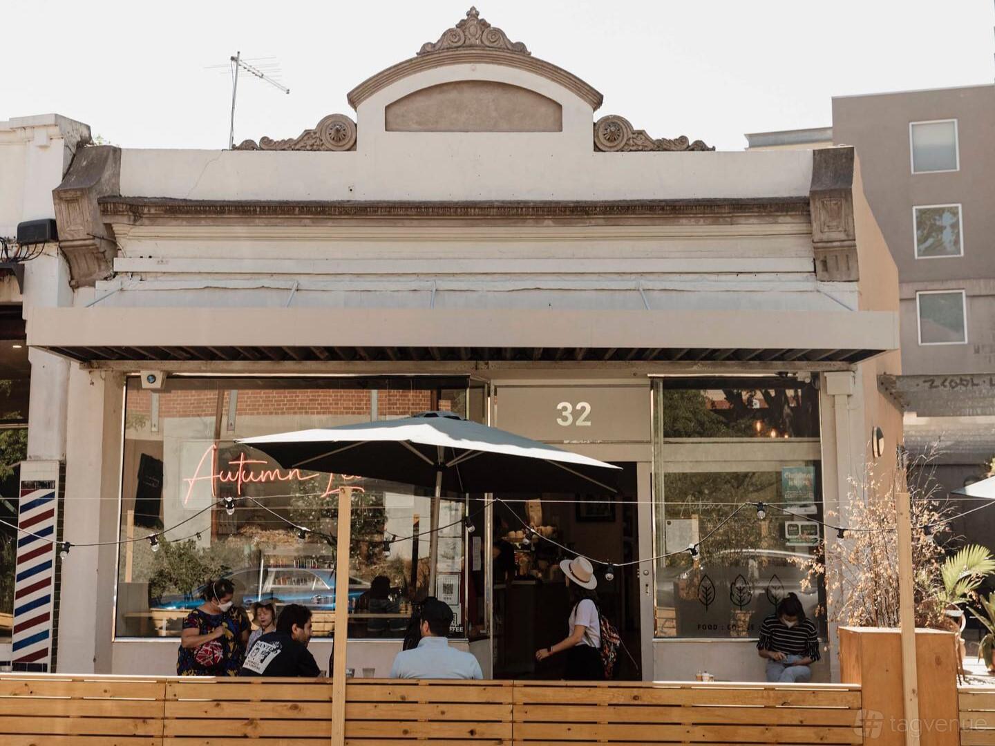 A restaurant with a street-facing outdoor seating area under a large umbrella at Autumn Leaves Melbourne.