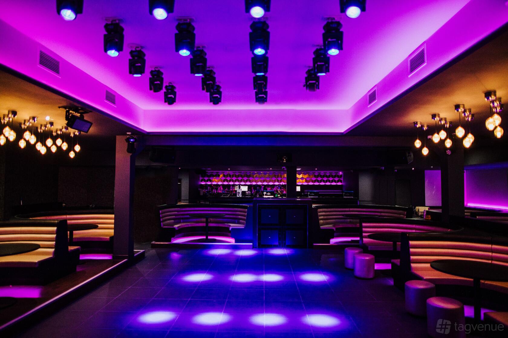 A nightclub with purple LED ceiling lights, circular booths, and a central dance floor at Faces.