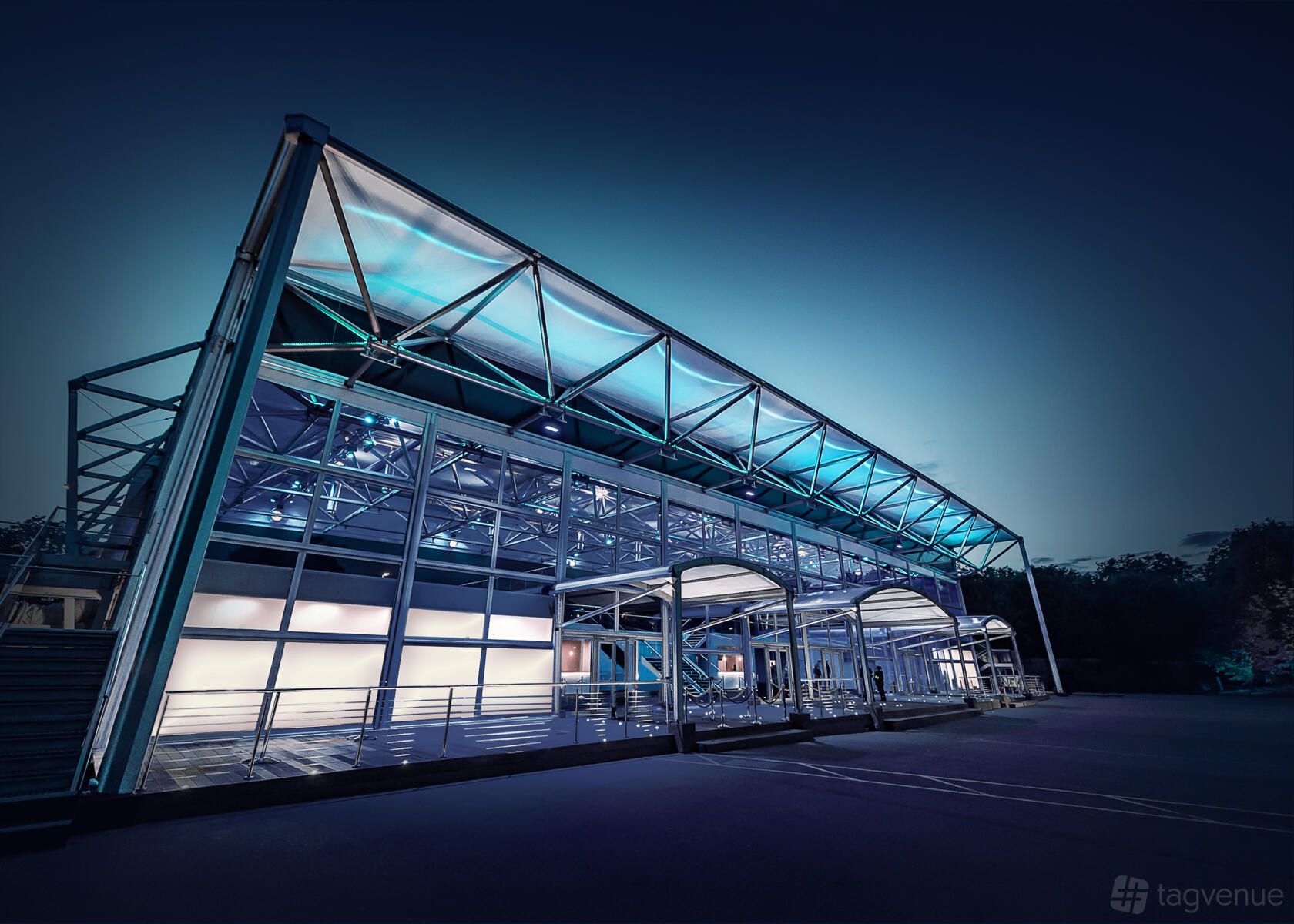 An event venue with a glass and steel exterior, illuminated blue lighting, and covered entry at Evolution London.