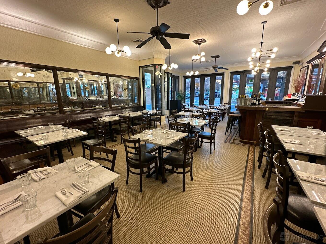 A restaurant dining room with marble-topped tables, dark wooden chairs, and wall-length mirrors at Brasserie Le Mistral.