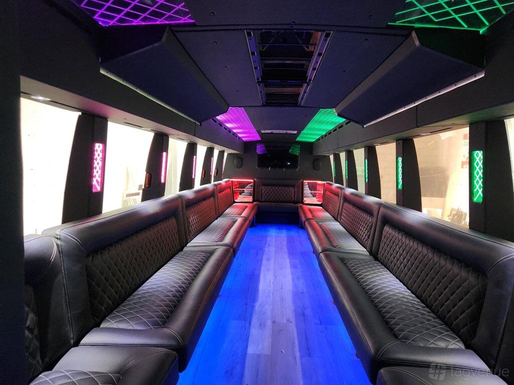 A party bus with quilted leather bench seating, color-changing LED lights, and wood-style flooring at KVM Limousine Services.