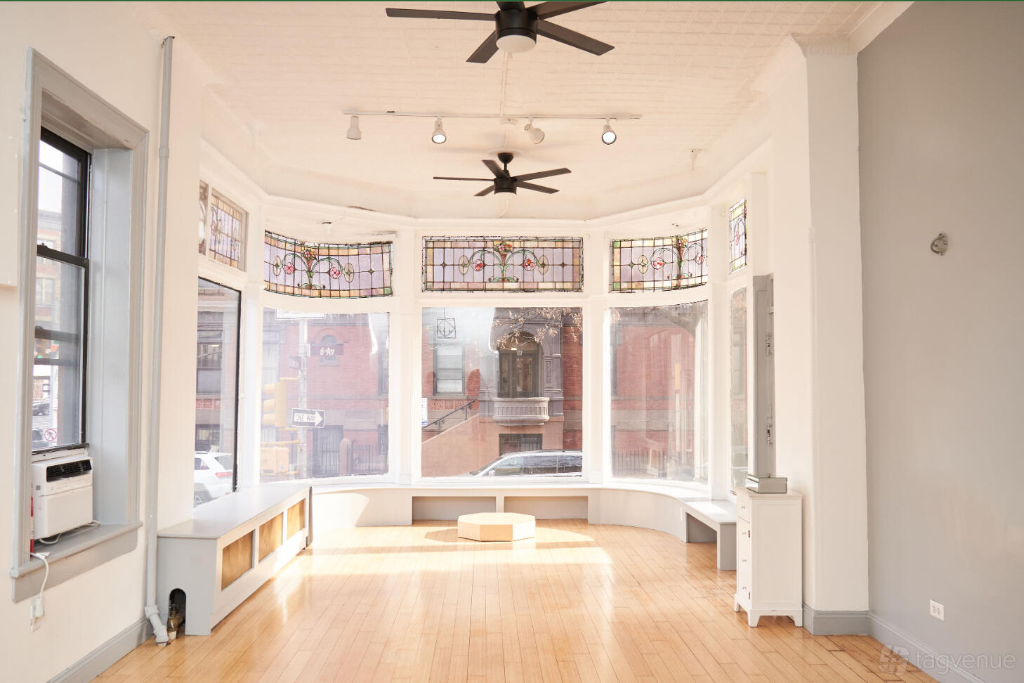 An apartment with bay windows, hardwood floors, stained glass accents, and a ceiling fan at Atrium82™.