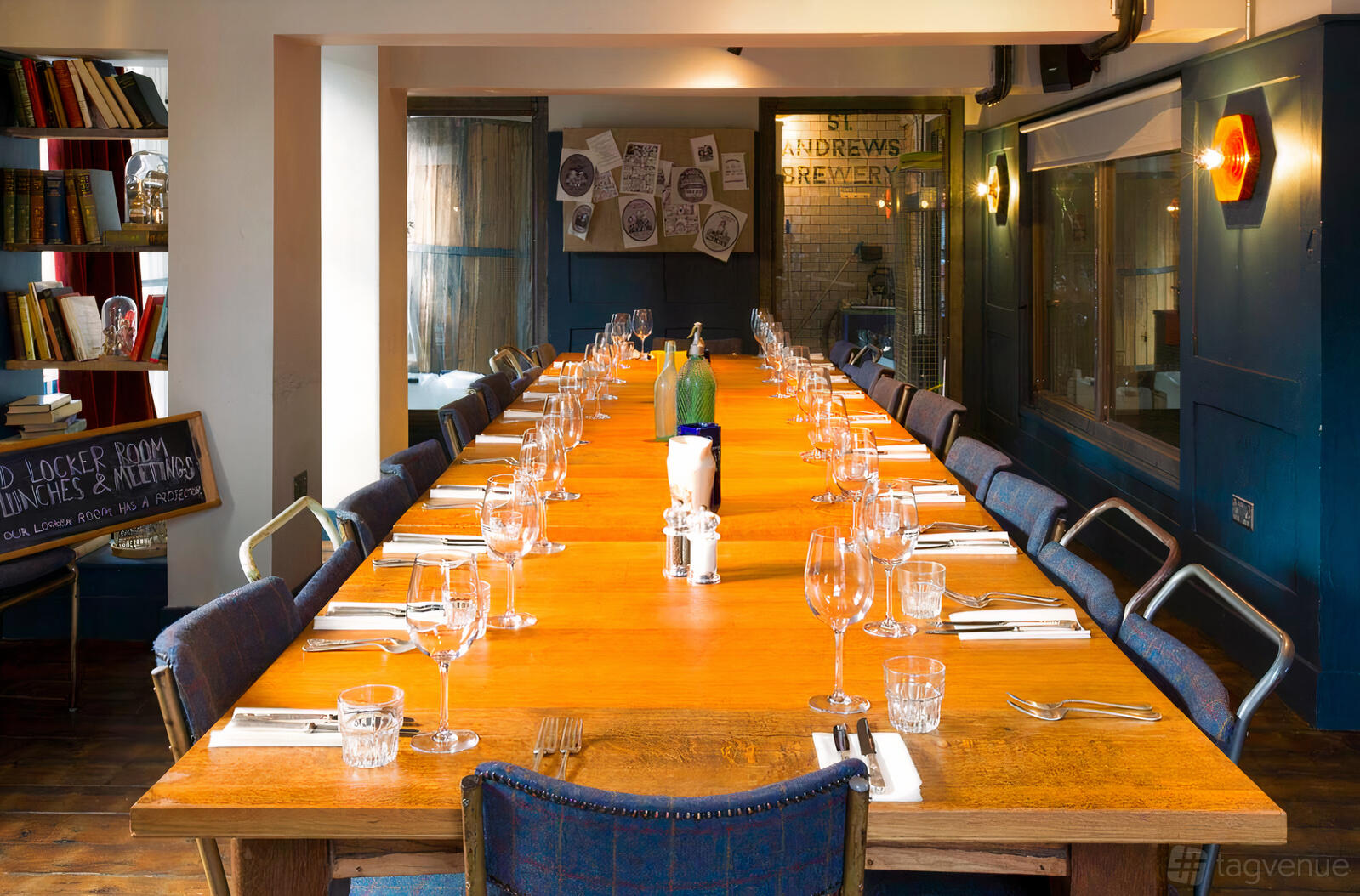 A private dining room with a long wooden table, blue chairs, and glassware set at St Andrews Brewhouse.