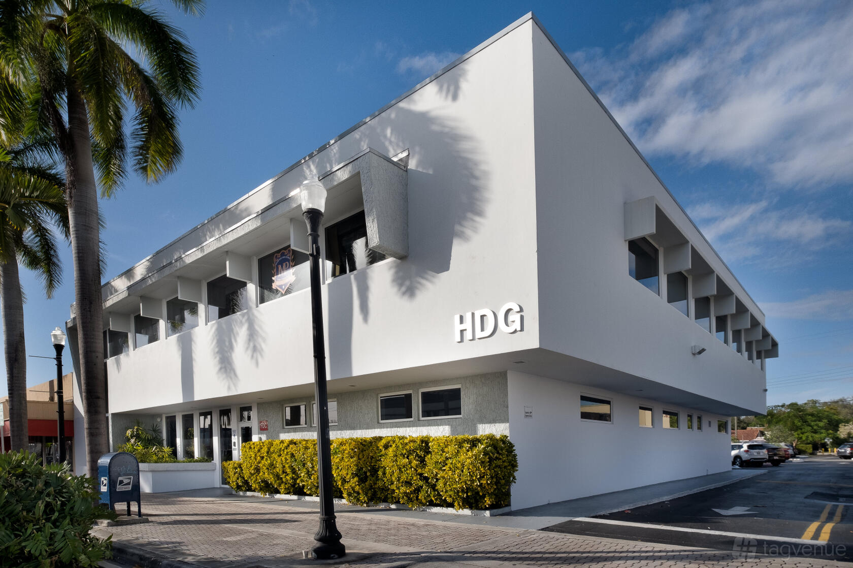A meeting centre with a white modern facade, large windows, and palm trees at HDG Executive Suites.