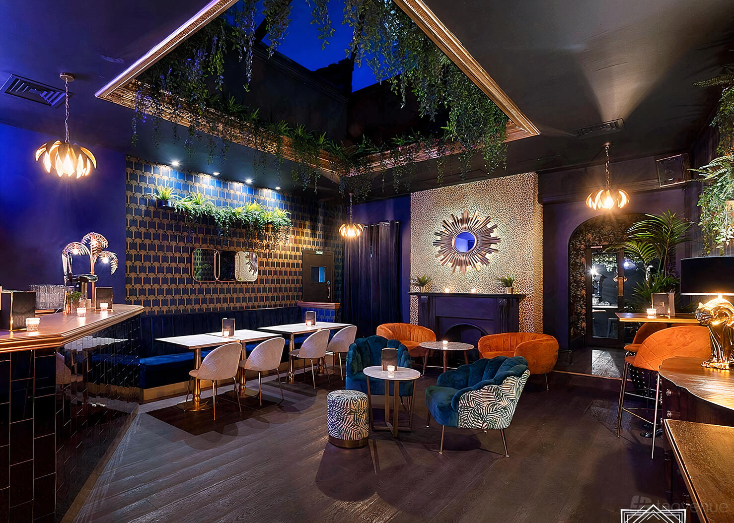 A function room in a cocktail bar with velvet armchairs, patterned wallpaper, and greenery at Lost Society (Battersea SW11).