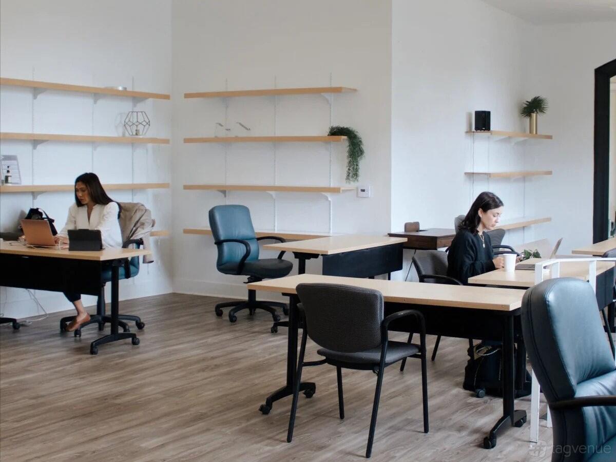 A coworking space with wood flooring, modern desks, and minimalist wall shelves at The New Haven - Coworking with Preschool.