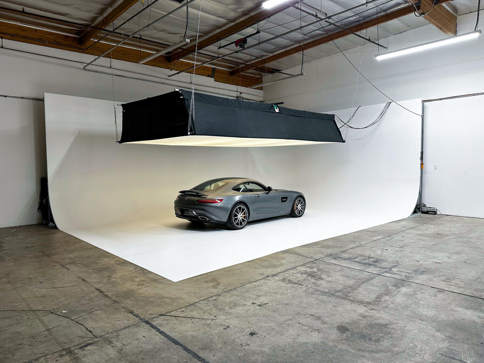 A photo studio with a white cyclorama wall, overhead lighting, and exposed ceilings at Heritage Gruppe Studio.
