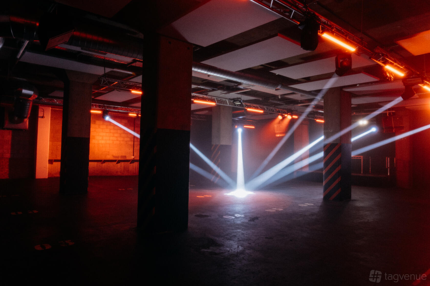 An industrial event venue with exposed pillars, dark floors, and dramatic lighting effects at Archives London.